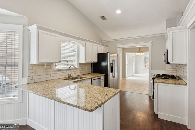 kitchen with sink, white cabinets, kitchen peninsula, stainless steel appliances, and light stone countertops