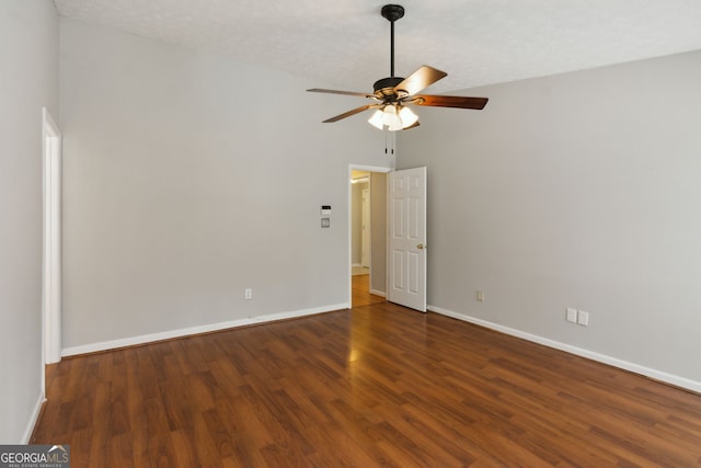 empty room featuring vaulted ceiling, dark wood-type flooring, a textured ceiling, and ceiling fan