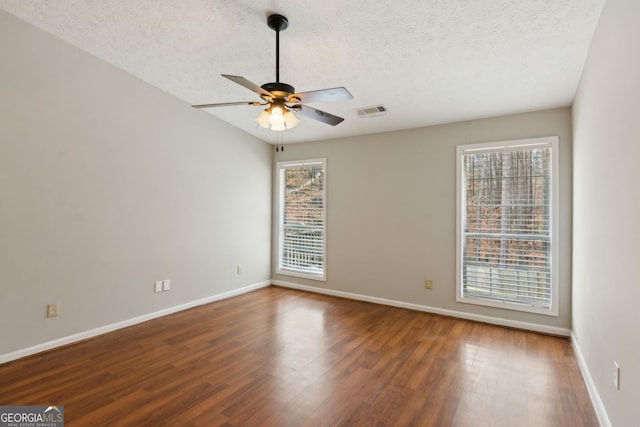 empty room with a textured ceiling, dark wood-type flooring, and ceiling fan