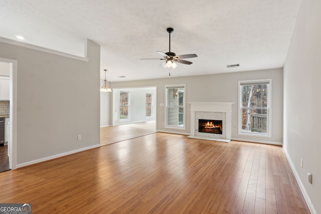 unfurnished living room featuring a premium fireplace, ceiling fan, and light wood-type flooring