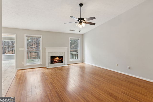 unfurnished living room featuring lofted ceiling, a fireplace, ceiling fan, and light wood-type flooring