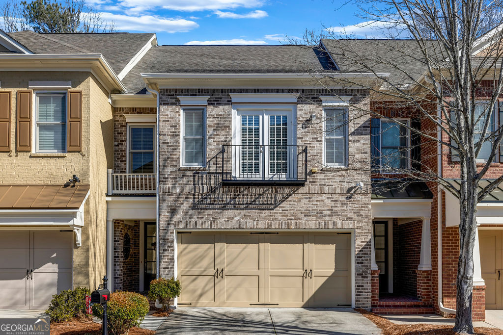 townhome / multi-family property featuring brick siding, driveway, an attached garage, and roof with shingles