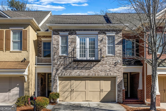 townhome / multi-family property featuring brick siding, driveway, an attached garage, and roof with shingles