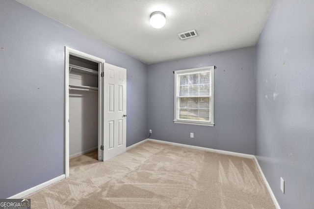 unfurnished bedroom featuring light colored carpet, a closet, and a textured ceiling