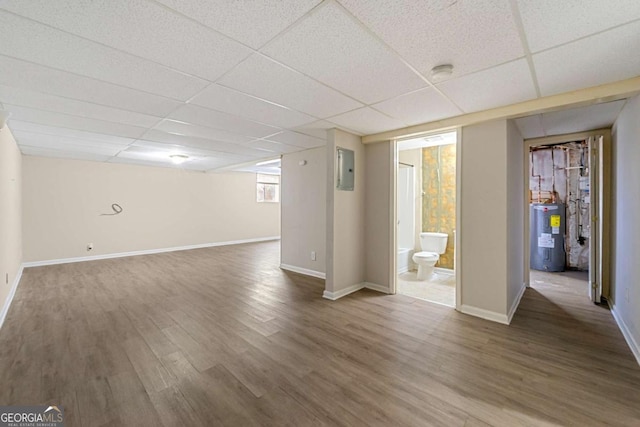 basement with a drop ceiling, hardwood / wood-style floors, and electric water heater