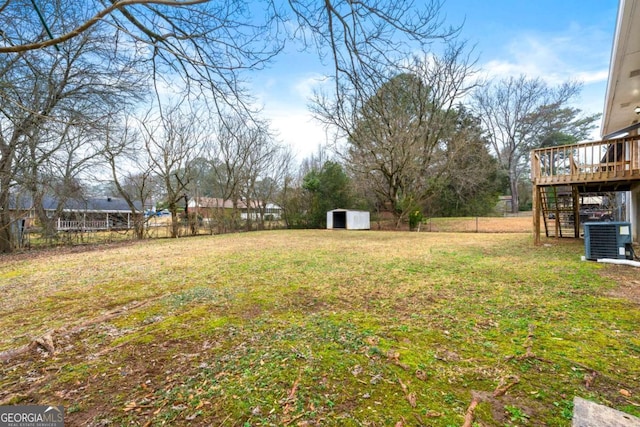 view of yard with a wooden deck, central AC, and a storage unit