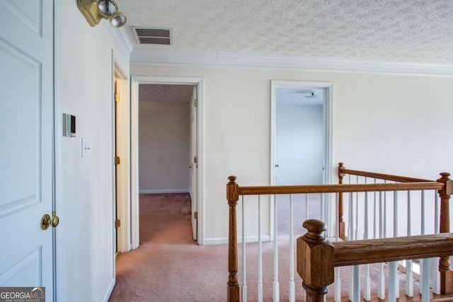 corridor featuring crown molding, light colored carpet, and a textured ceiling