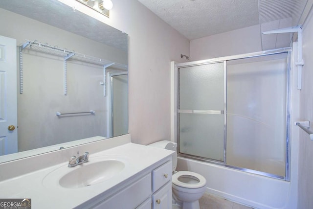 full bathroom with combined bath / shower with glass door, vanity, a textured ceiling, tile patterned floors, and toilet