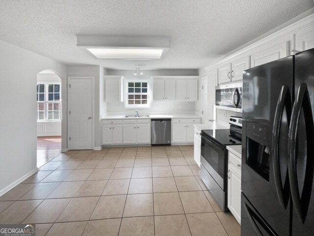 kitchen with sink, white cabinetry, a textured ceiling, light tile patterned floors, and stainless steel appliances