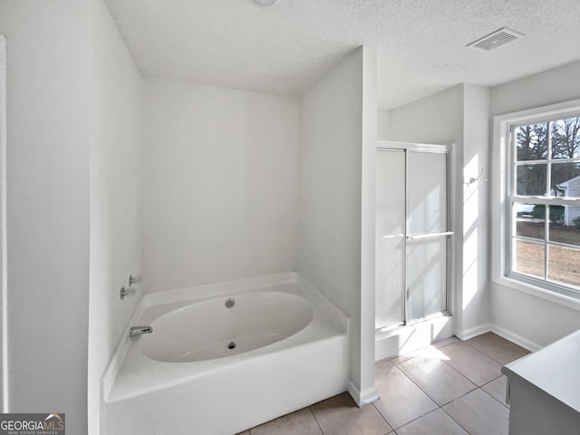 bathroom featuring tile patterned floors, independent shower and bath, a textured ceiling, and a wealth of natural light