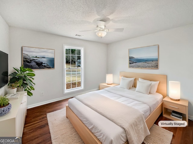 bedroom with ceiling fan, dark hardwood / wood-style floors, and a textured ceiling