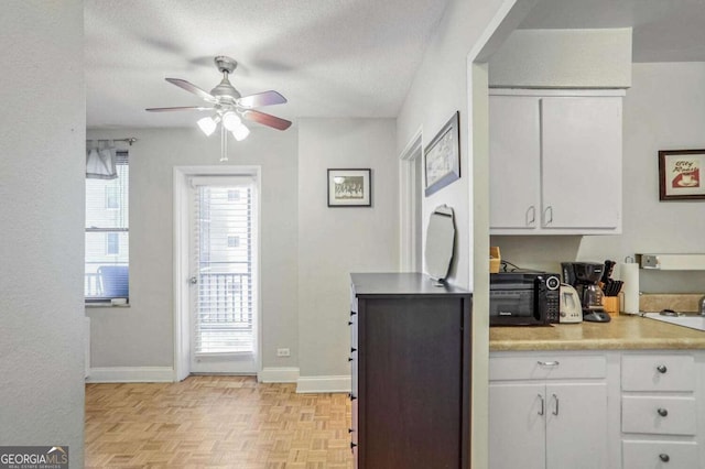 kitchen featuring white cabinetry, light parquet flooring, ceiling fan, and a textured ceiling