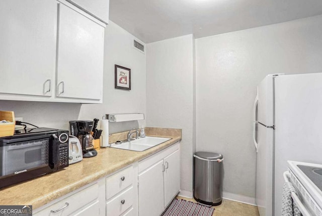 kitchen with range, sink, white fridge, and white cabinets