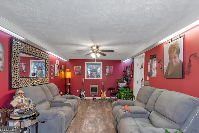 living room with ceiling fan, wood-type flooring, heating unit, and a textured ceiling