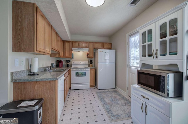 kitchen with white appliances, sink, a textured ceiling, and white cabinets