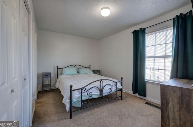 carpeted bedroom with a closet and a textured ceiling