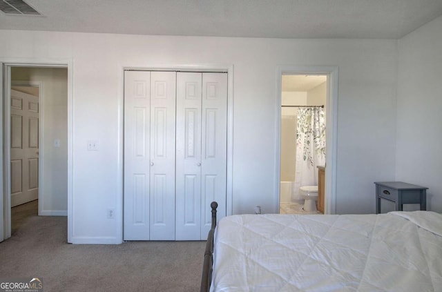 bedroom with a closet, ensuite bathroom, and light carpet