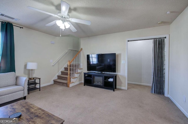 living room featuring ceiling fan, light carpet, and a textured ceiling