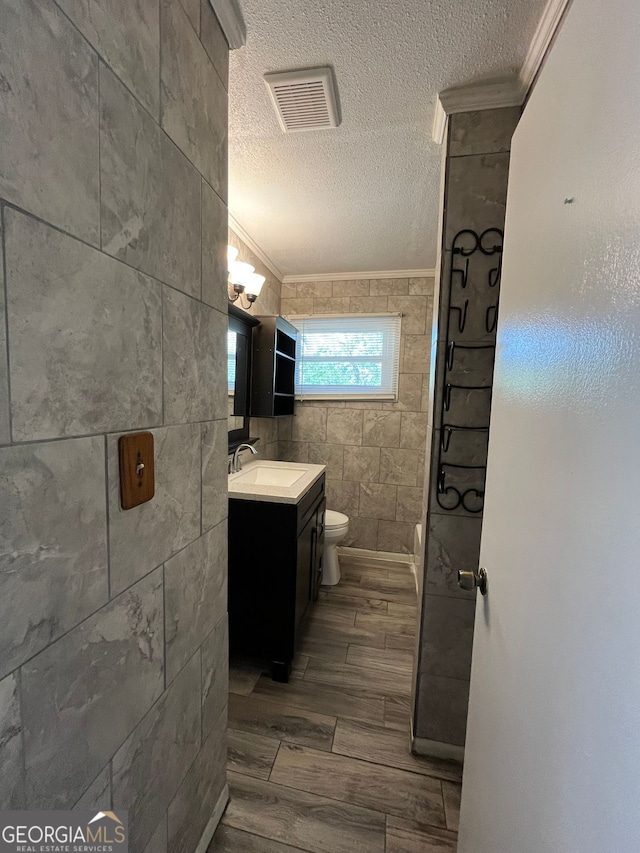 bathroom featuring crown molding, tile walls, vanity, a textured ceiling, and toilet