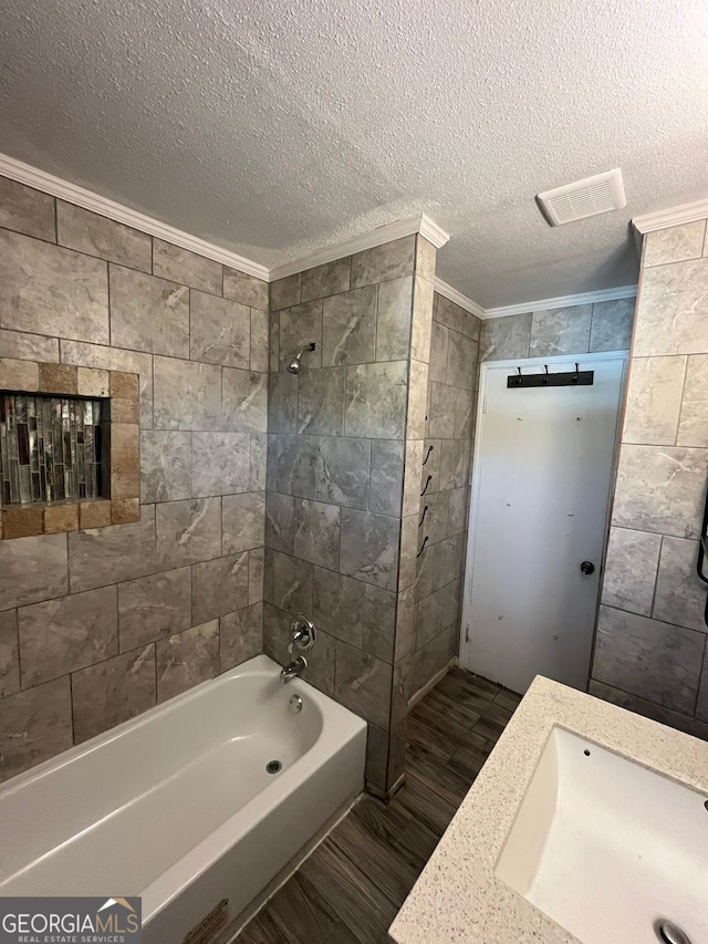 bathroom with tiled shower / bath, wood-type flooring, sink, crown molding, and a textured ceiling