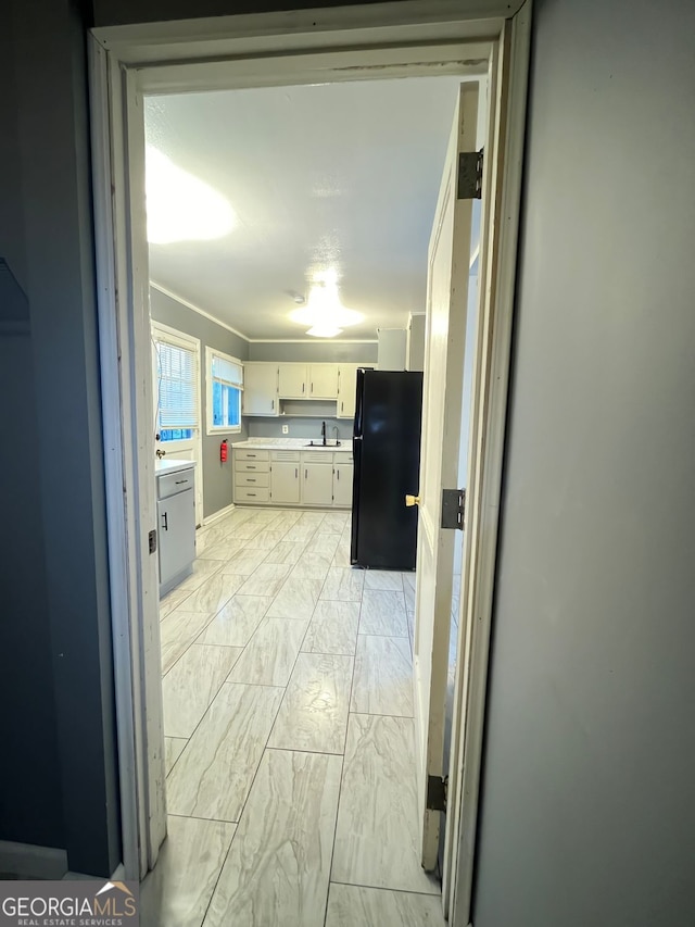 kitchen featuring black refrigerator, sink, and cream cabinetry