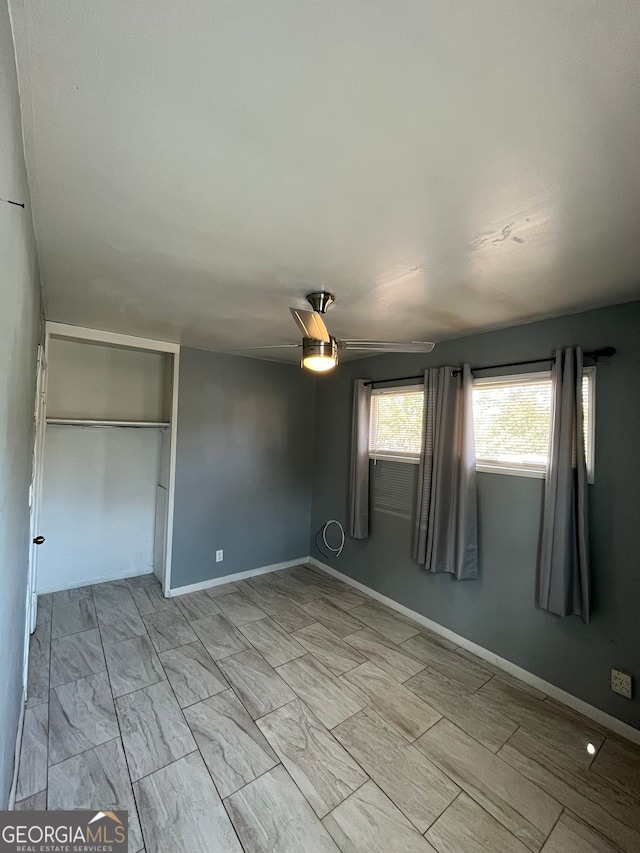 unfurnished bedroom featuring ceiling fan and a closet