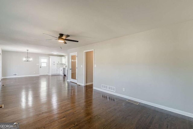 spare room featuring dark wood-type flooring and ceiling fan with notable chandelier