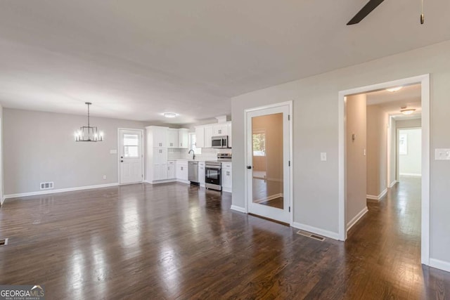 unfurnished living room with sink, dark wood-type flooring, and ceiling fan with notable chandelier