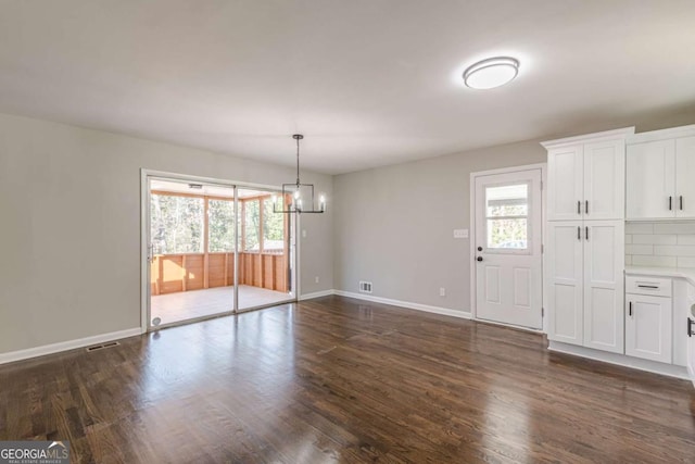 unfurnished dining area with dark hardwood / wood-style flooring, a healthy amount of sunlight, and an inviting chandelier