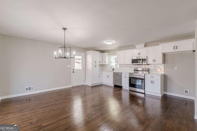 kitchen featuring sink, white cabinetry, stainless steel appliances, dark hardwood / wood-style floors, and decorative backsplash