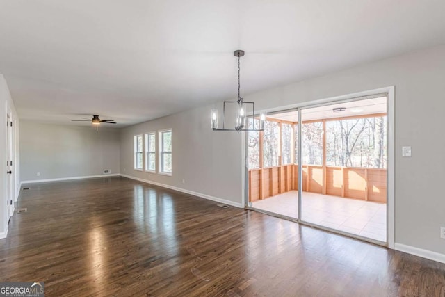 unfurnished dining area with dark hardwood / wood-style flooring and ceiling fan with notable chandelier