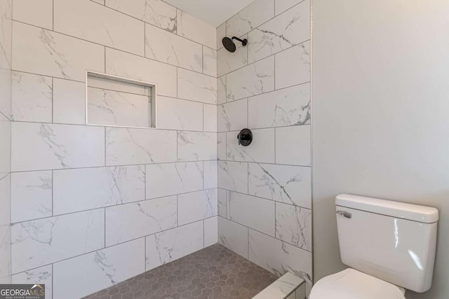 bathroom featuring a tile shower and toilet