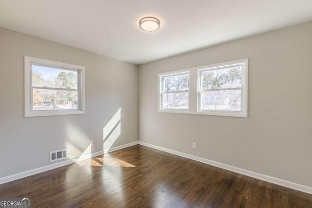 unfurnished room with a healthy amount of sunlight and dark hardwood / wood-style flooring