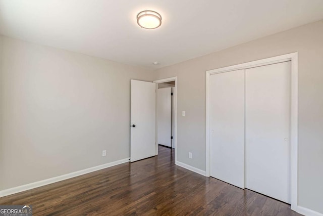 unfurnished bedroom featuring dark wood-type flooring and a closet