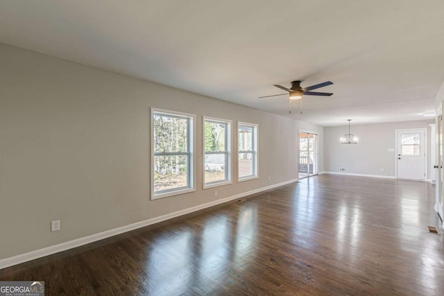 unfurnished room featuring ceiling fan with notable chandelier and dark wood-type flooring