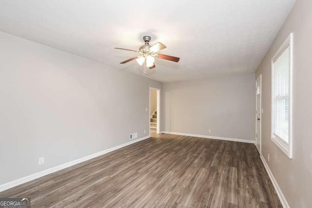 empty room with dark hardwood / wood-style floors and ceiling fan