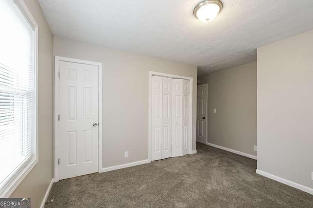 unfurnished bedroom featuring dark carpet and a textured ceiling