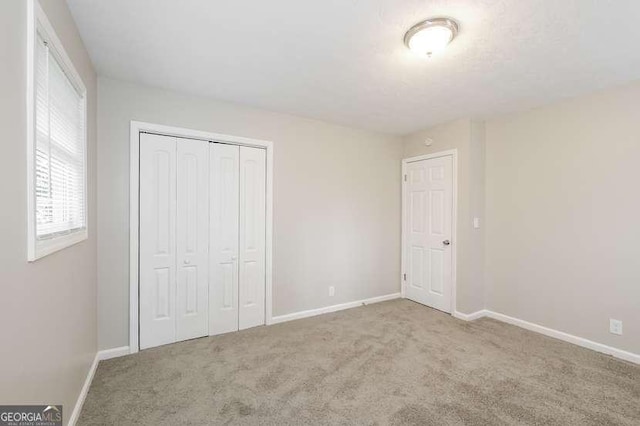 unfurnished bedroom with a closet and light carpet