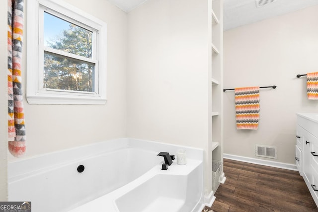 bathroom with hardwood / wood-style flooring, vanity, and a tub to relax in