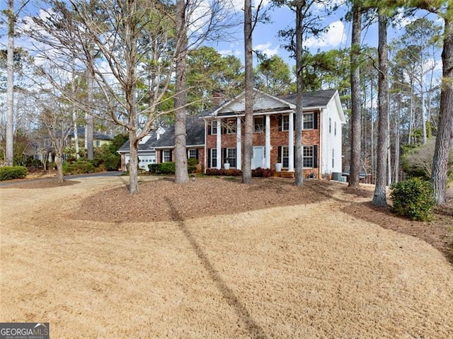 neoclassical home with dirt driveway and brick siding