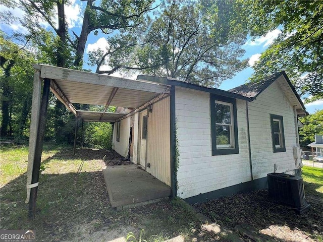 view of side of property featuring a carport and central AC