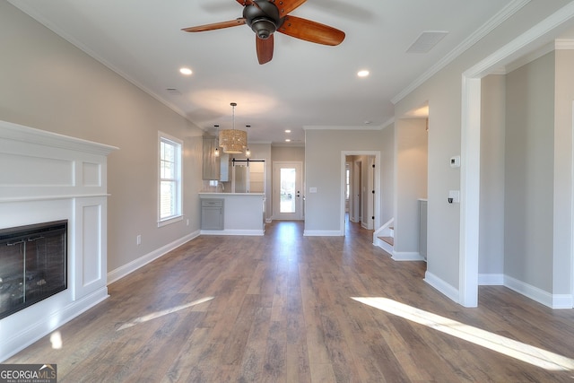 unfurnished living room featuring hardwood / wood-style flooring, ceiling fan, and crown molding