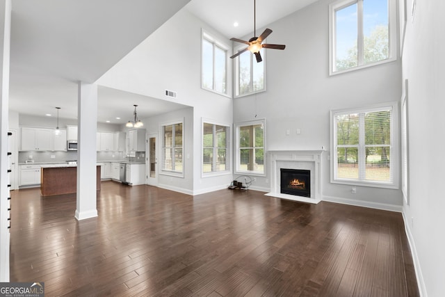 unfurnished living room featuring ceiling fan, dark hardwood / wood-style floors, and a wealth of natural light