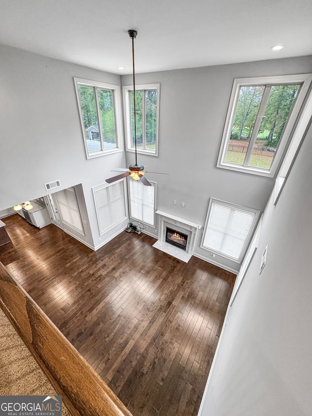 living room with ceiling fan, a premium fireplace, and dark hardwood / wood-style flooring