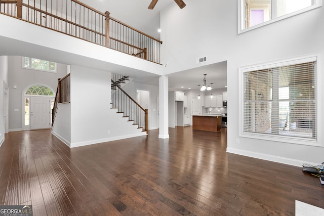 unfurnished living room with a high ceiling, dark hardwood / wood-style floors, and ceiling fan