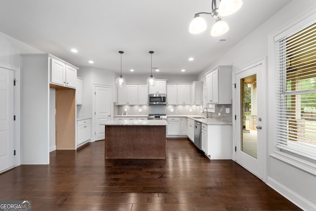 kitchen featuring pendant lighting, sink, stainless steel appliances, a center island, and white cabinets