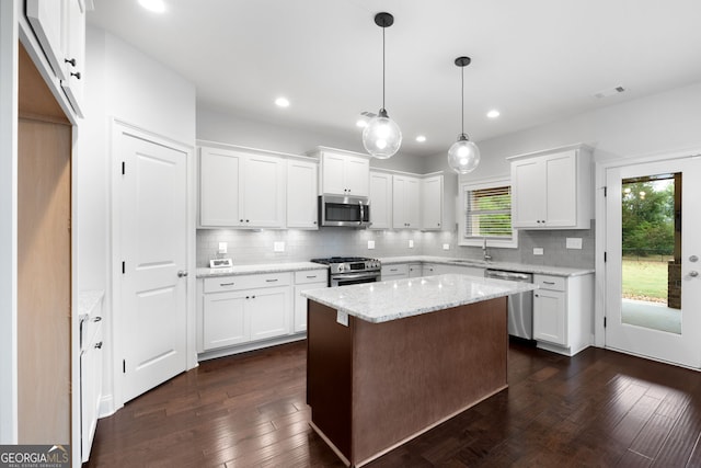 kitchen with appliances with stainless steel finishes, sink, white cabinets, hanging light fixtures, and light stone counters