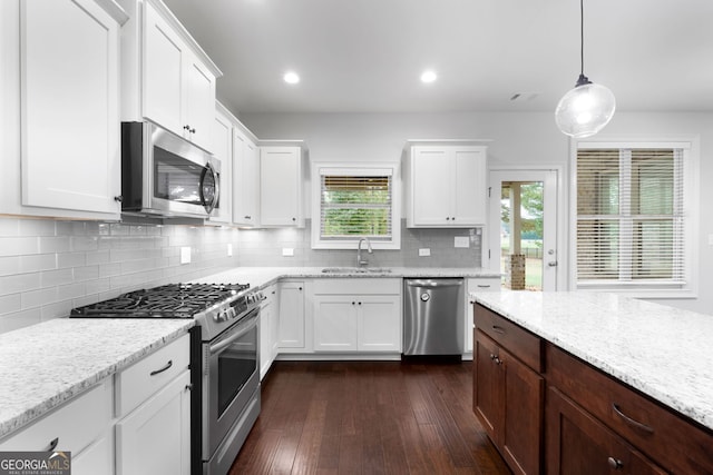 kitchen featuring hanging light fixtures, appliances with stainless steel finishes, sink, and white cabinets