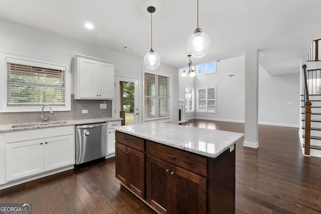 kitchen with pendant lighting, sink, dishwasher, white cabinetry, and light stone countertops