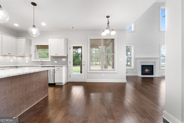 kitchen with pendant lighting, dark wood-type flooring, light stone countertops, and white cabinets